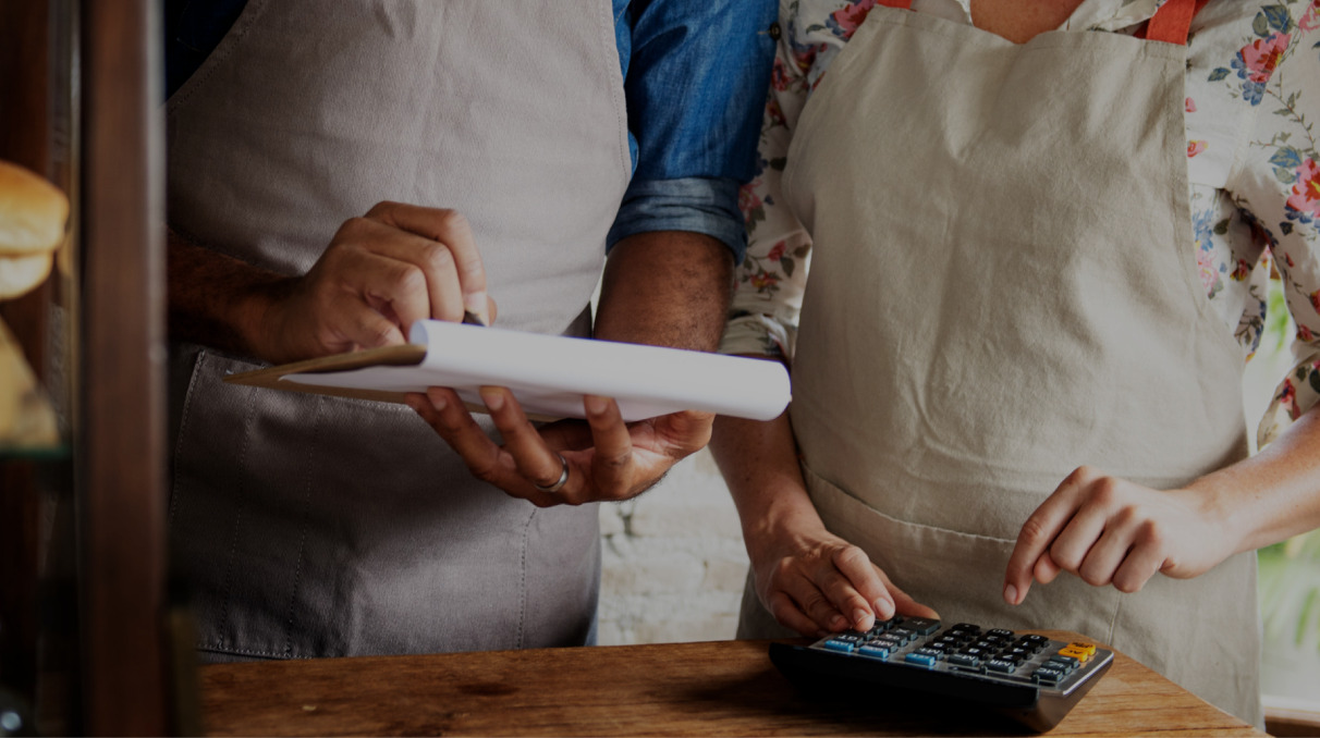Restaurant staff reviewing paperwork and using a calculator to manage costs and expenses